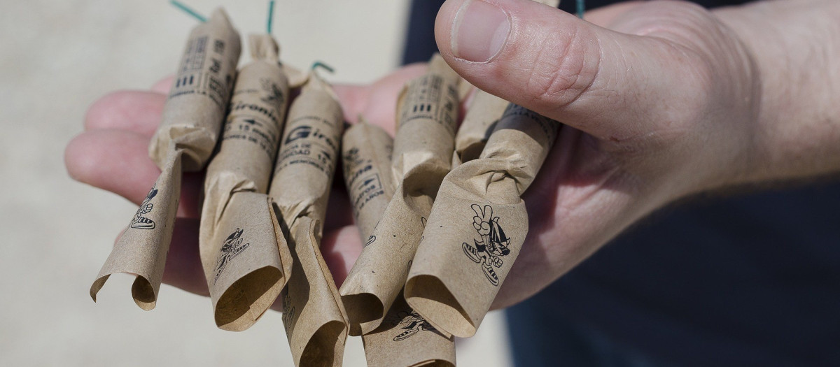 Un hombre sostiene en su mano unos petardos