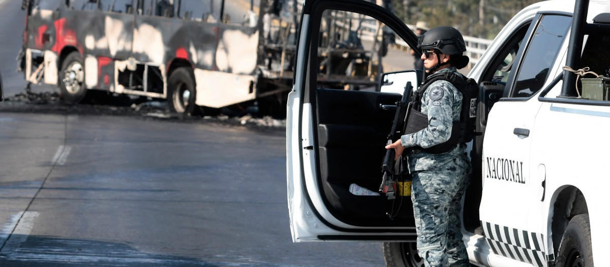 Un miembro de la Guardia Nacional se encuentra cerca de un autobús incendiado por grupos del crimen organizado
