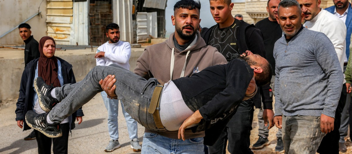 Un hombre lleva en brazos a un palestino afectado por gases lacrimógenos disparados por las fuerzas de seguridad israelíes.