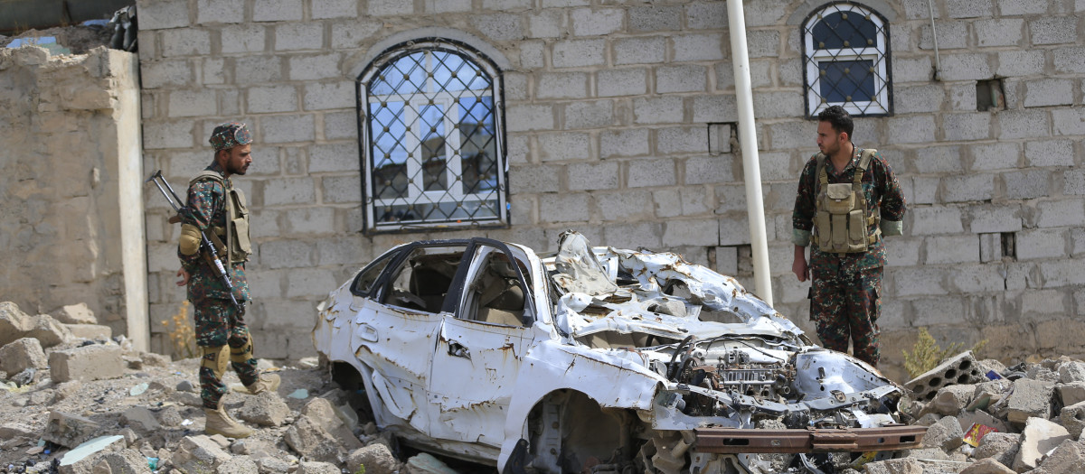 Soldados yemeníes permanecen de pie sobre los escombros de un edificio y los restos de un automóvil destruidos por los ataques aéreos saudíes
