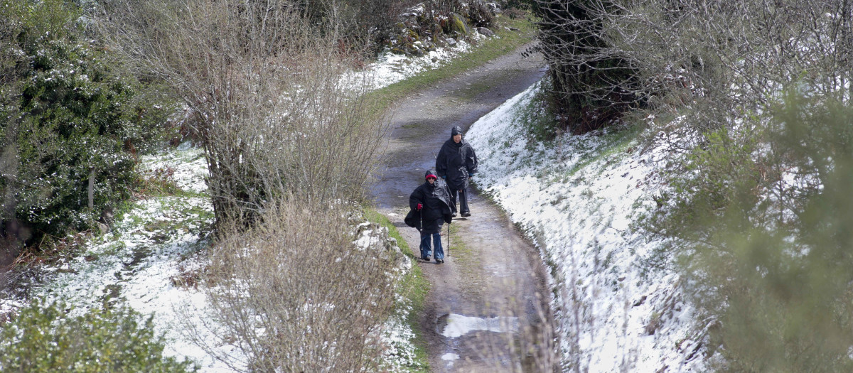Dos peregrinos caminan entre la nieve en Liñares
