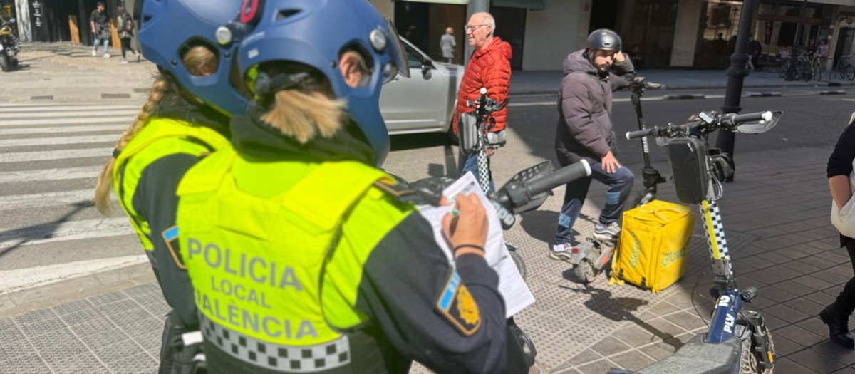 Dos agentes de la nueva unidad de la Policía Local de Valencia multan al conductor de un patinete.