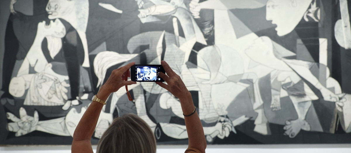 Una mujer fotografía la obra de Picasso 'Guernica' durante la presentación de los actos conmemorativos del Año Picasso, en el Museo Reina Sofía