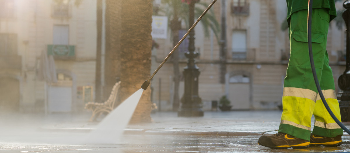 Un operario utiliza una manguera a presión para limpiar la calle