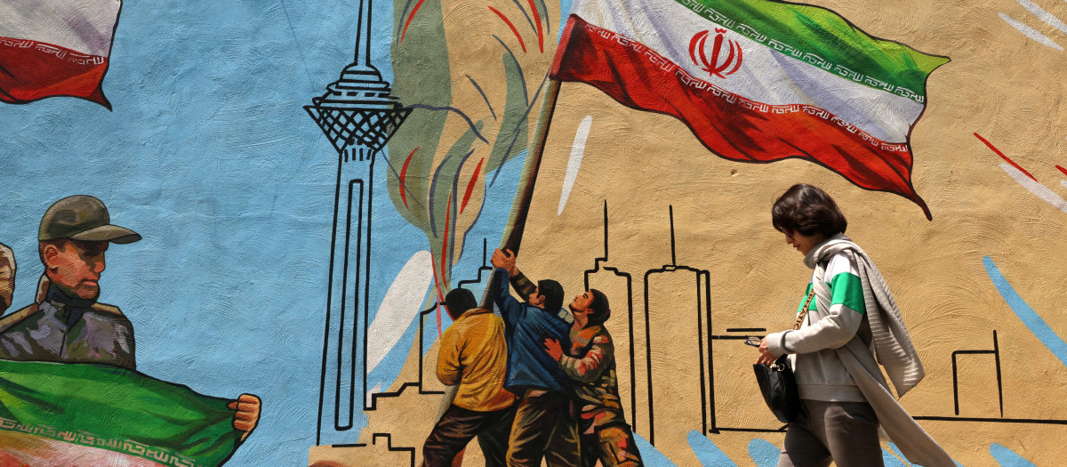 Una mujer iraní pasa junto a un mural antiestadounidense y antiisraelí en Teherán