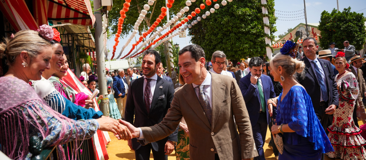 El presidente de la Junta, Juanma Moreno, saluda a unas flamencas en el Real de la Feria de Abril de Sevilla