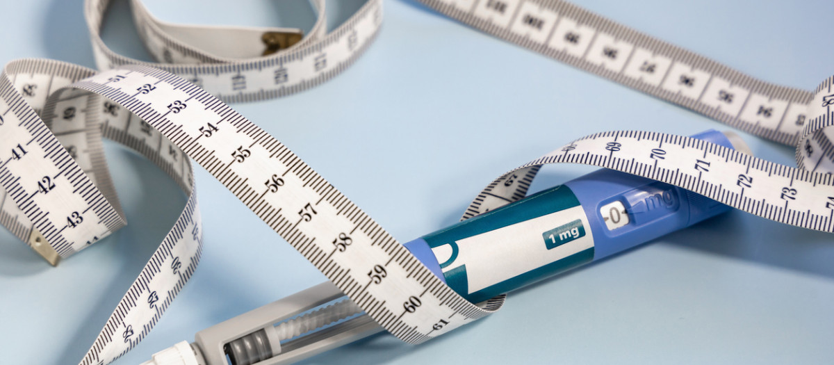 Ozempic syringe pen and measuring tape on blue background.