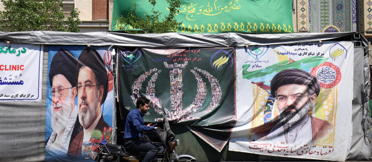 Un automovilista pasa junto a pancartas instaladas a lo largo de la carretera con imágenes del líder supremo asesinado de Irán, el ayatolá Ali Khamenei (izquierda), y del líder supremo, el ayatolá Mojtaba Khamenei, en Teherán