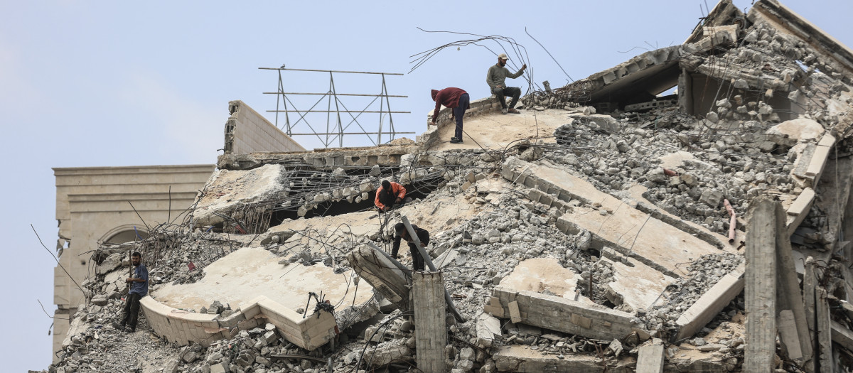 Hombres palestinos se encuentran en lo alto de un edificio gravemente dañado en la ciudad de Gaza