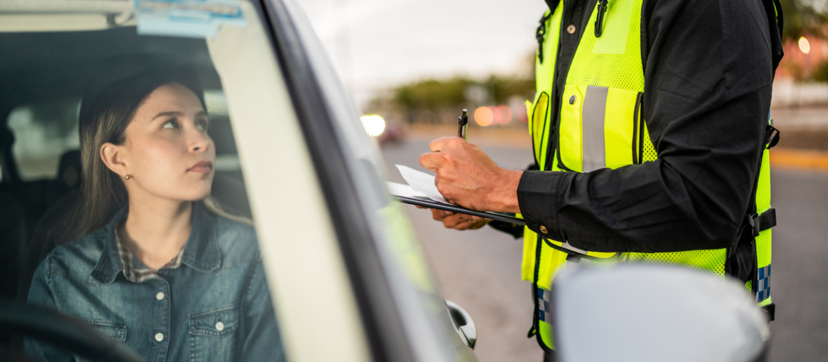 Mid adult traffic cop ticketing young woman on city street