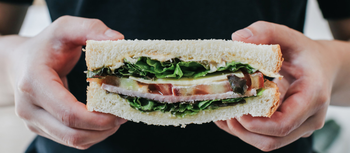 Presentación de un sándwich casero de jamón, bacon, tomate, queso y lechuga