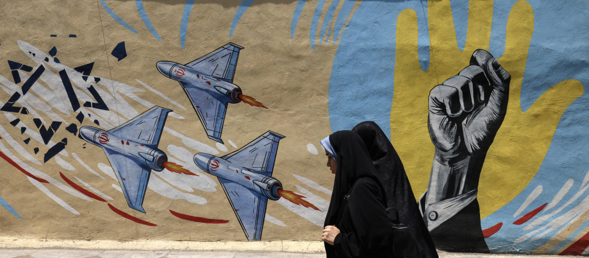 Mujeres iraníes pasan junto a un mural antiestadounidense y antiisraelí en Teherán