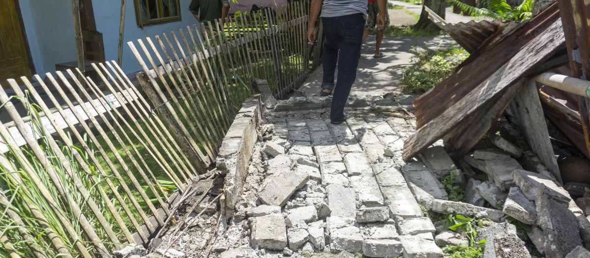 Personas observan los daños causados ​​por un terremoto de magnitud 7,8 en una zona residencial frente a las costas del sur de Filipinas