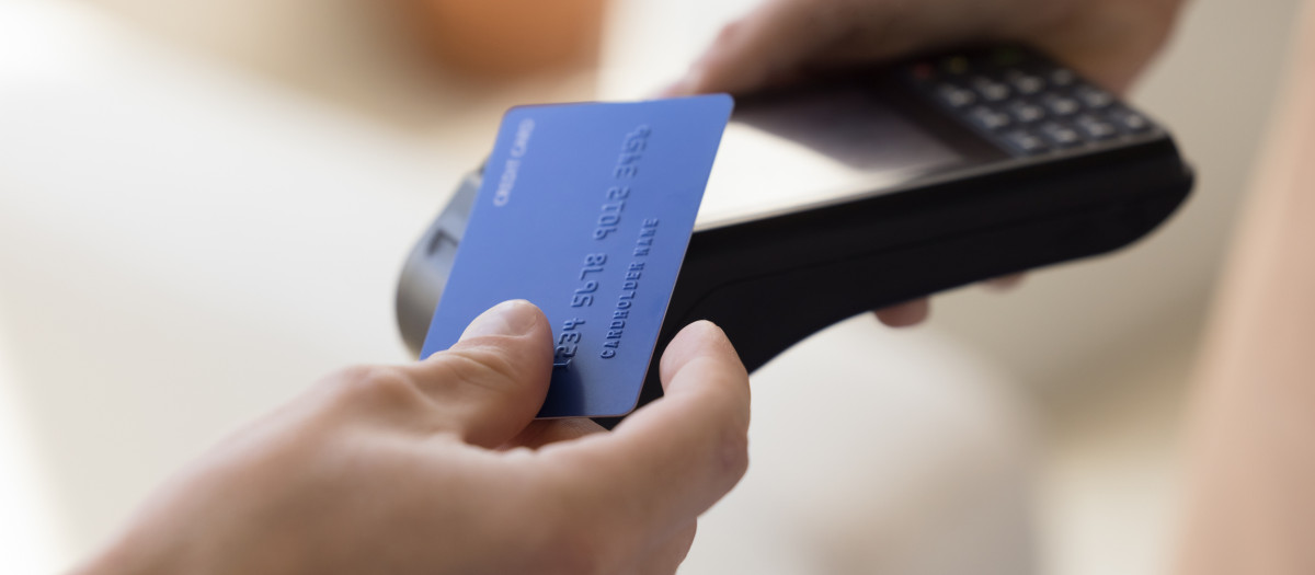 Una persona acercando su tarjeta de crédito a un datáfono para pagar