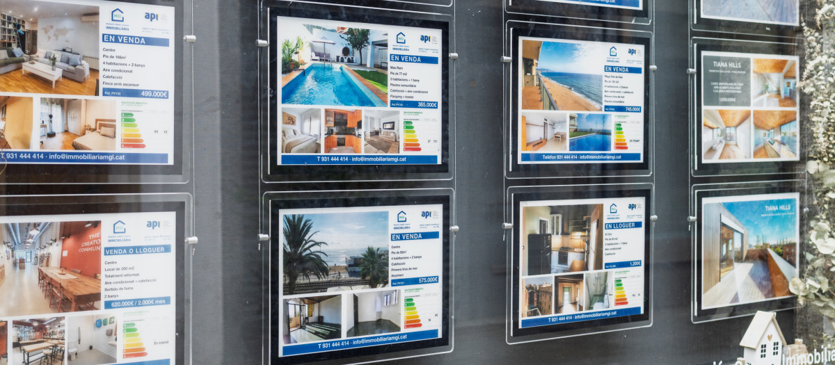 Badalona, Spain - February 3, 2026: Exterior display of a real estate agency featuring photos, prices, and energy ratings of apartments for sale and rent.