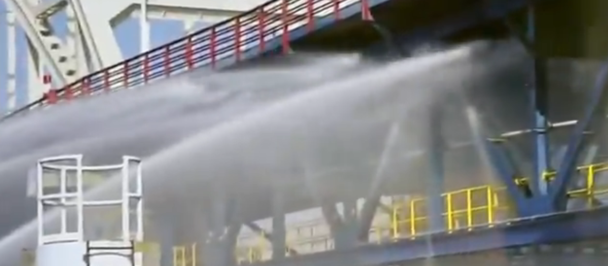 Imagen de los operarios de bomberos dirigiendo el agua a un puente