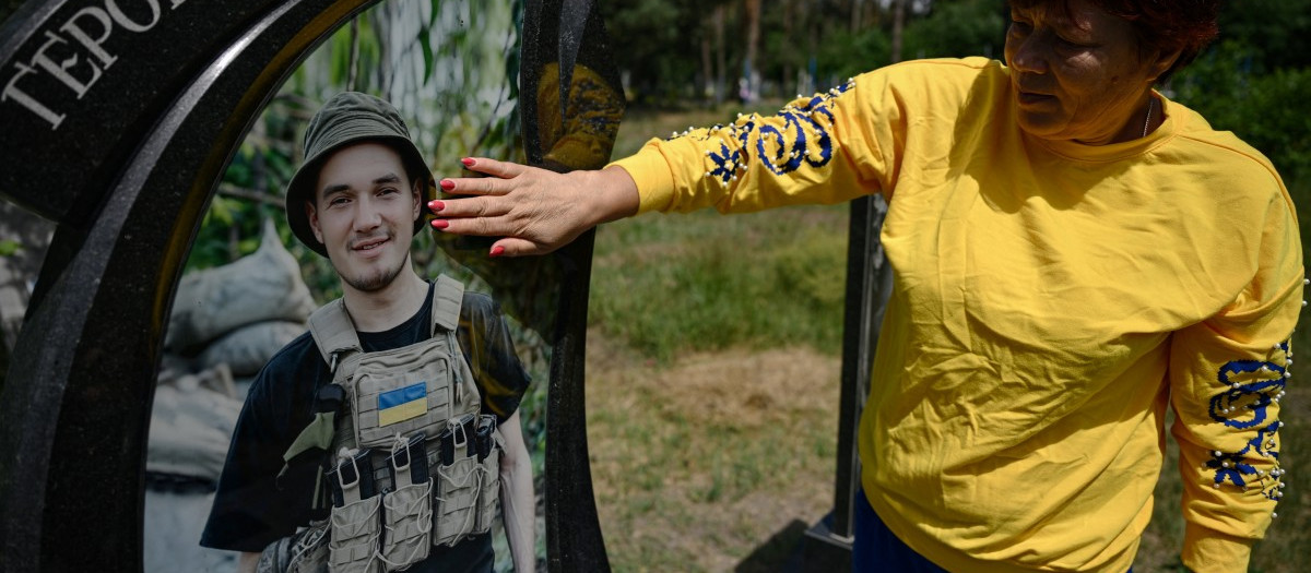 Mother of the late Ukrainian serviceman Andriy Dubnytsky, Nadia, 57, touches his portrait as she visit his grave at a cemetery in the Stepantsi village, Cherkasy region, on July 7, 2026, amid the Russian invasion of Ukraine. In the last message Liudmyla Dubnytska received from her husband, he told her he was likely about to be captured by Russian forces. Two days later, she recognised his body in a video on social media of a group of killed Ukrainian troops. (Photo by Genya SAVILOV / AFP)