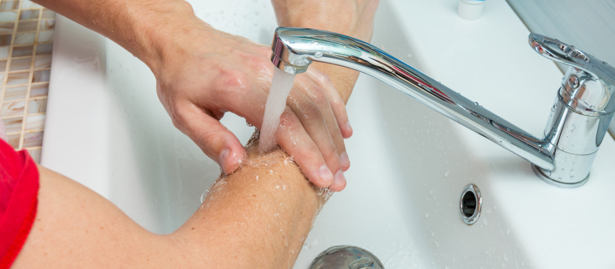 A man washes his hands up to the elbows under the tap