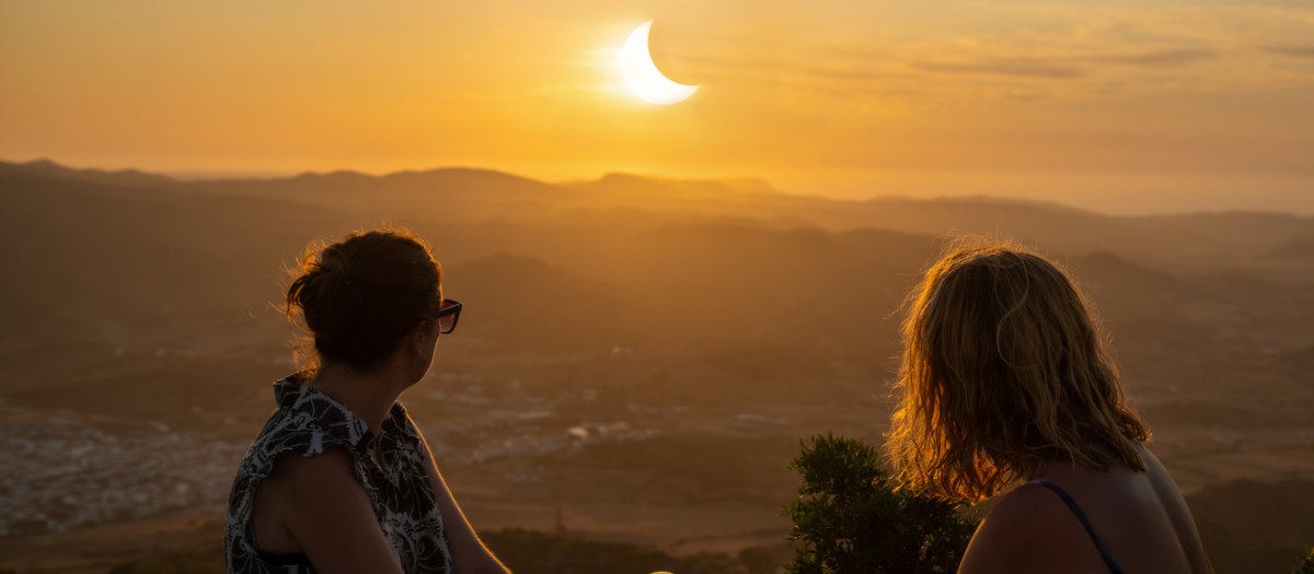 Dos personas mirando un espectacular eclipse solar parcial