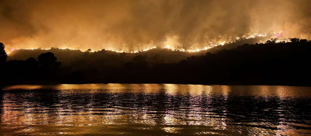 Impresionante imagen del pantano de San Juan rodeado por las llamas
