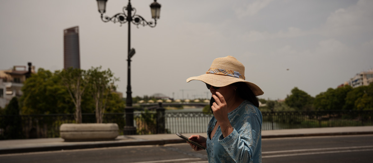 Una mujer se protege del sol con un sombrero en Sevilla