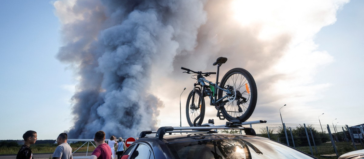 Bystanders watch as smoke rises from a fire at the Russian e-commerce firm Wildberries' logistics complexes in the town of Elektrostal outside Moscow on July 18, 2026. A Ukrainian drone attack on two logistics centres in Russia killed eight people and injured 24, officials said on July 18, 2026, when the Moscow region reported a new wave of drone strikes. Russian e-commerce firm Wildberries said its logistics complexes in Kotovsk and Elektrostal, in the Tambov and Moscow regions respectively, came under attack. One person was killed and 37 were injured at the Elektrostal warehouse, according to the region's governor, Andrei Vorobyov. (Photo by TATYANA MAKEYEVA / AFP)
