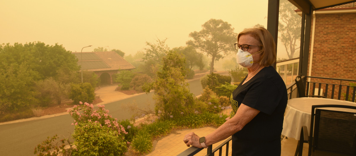 Una mujer, en un balcón, usa una máscara facial para protegerse contra un nivel muy peligroso de contaminación del aire