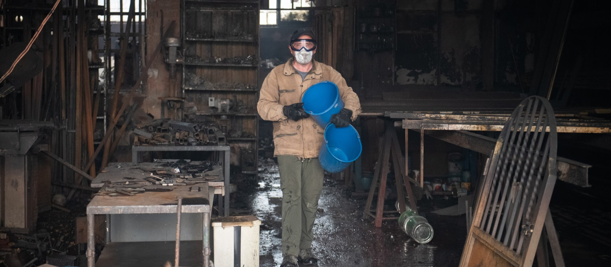 Una persona apagando fuegos en viviendas y naves en Piedralaves, durante el incendio de Burgohondo