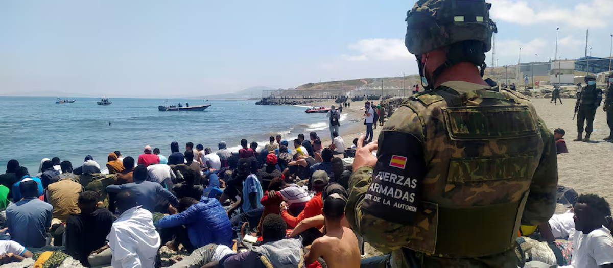 Un soldado del Ejército de Tierra observa a un grupo de inmigrantes que han logrado cruzar uno de los espigones fronterizos de Ceuta