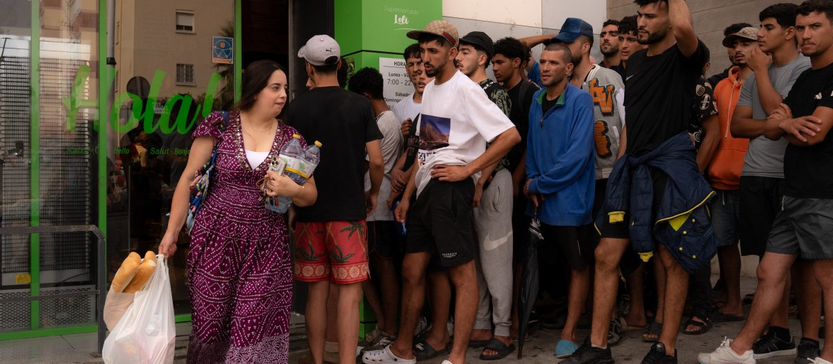 Una joven sale del supermercado mientras varios jóvenes la miran.