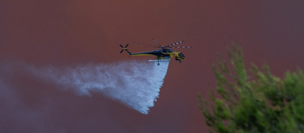 Un helicóptero de extinción de incendios arroja agua sobre un incendio forestal en la zona de Porto Germeno, a unos 70 kilómetros (45 millas) al noroeste de Atenas
