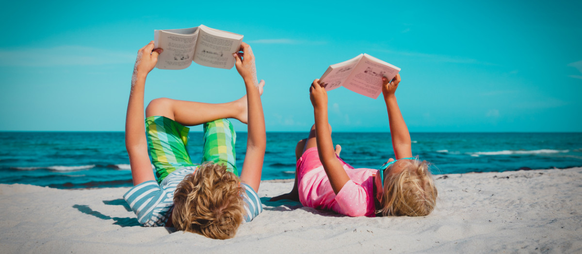 Dos niños leyendo en la playa