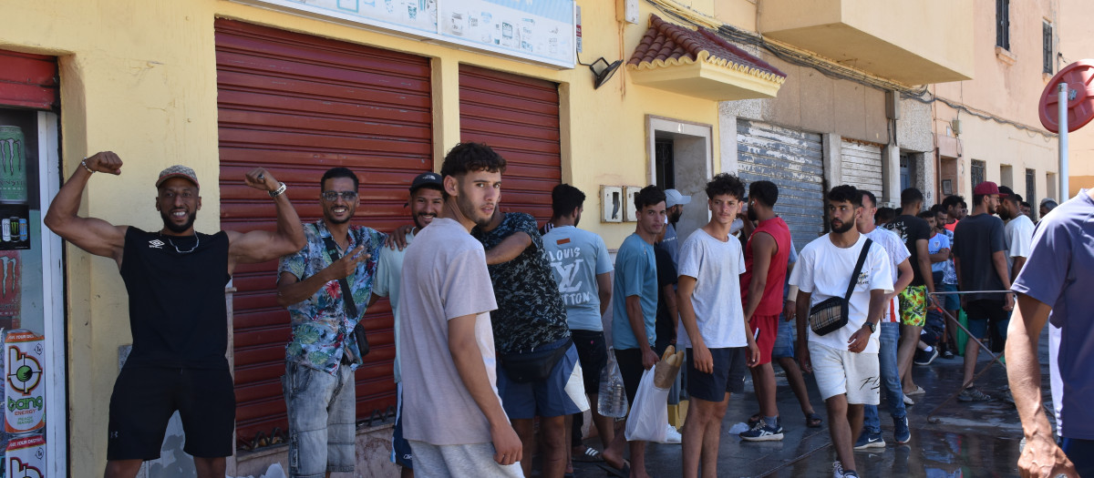 Varios inmigrantes hacen cola en un punto de atención humanitaria de Ceuta