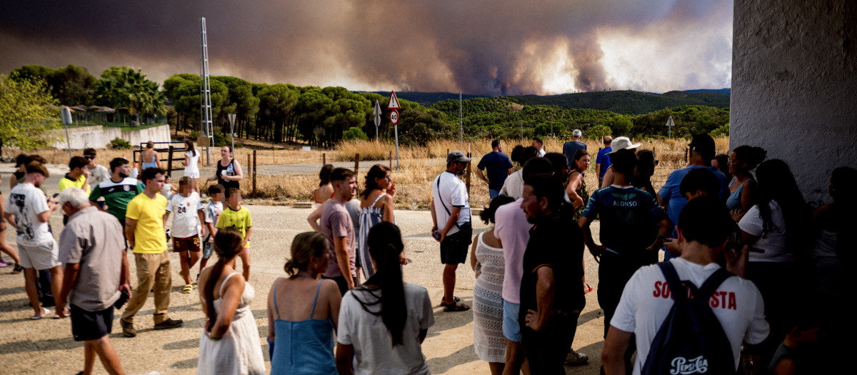 Vecinos de El Madroño, en Sevilla, observan este domingoo el fuego del incendio de Niebla (Huelva)