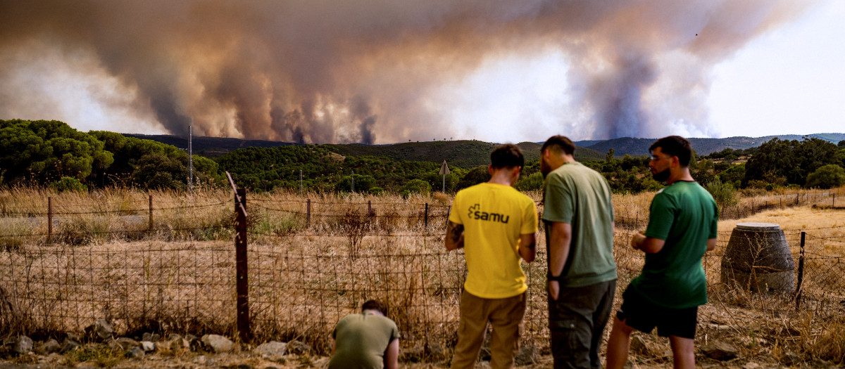 Vecinos de El Madroño, en Sevilla, observan este domingoo el fuego del incendio de Niebla (Huelva),