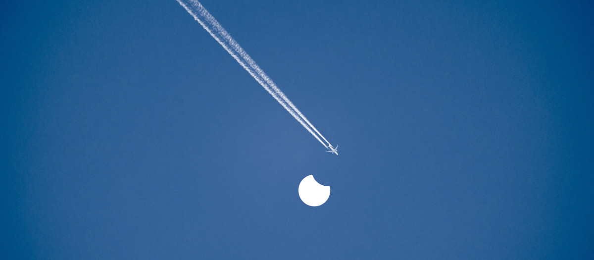 Un cielo despejado y con un eclipse solar parcial y un avión