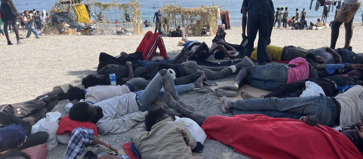 CEUTA, 09/08/2026.- Numerosos inmigrantes permanecen en la playa del Trampolín que se ha transformado en un asentamiento desde la entrada masiva registrada a finales de julio en la ciudad Ceuta.  EFE/Reduan