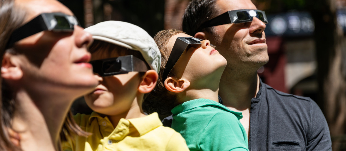 Una familia viendo un eclipse en la calle