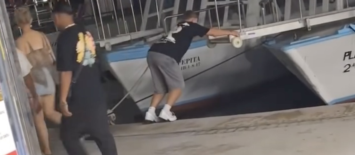 El joven turista en el momento de saltar a la pasarela.