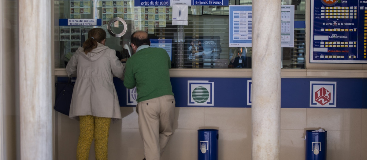 Imagen de archivo de dos personas compran lotería en una Administración