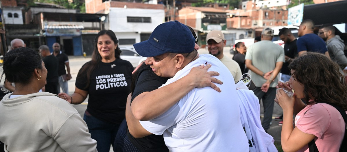Venezuelan activist Andreina Baduel embraces a released political prisoner outside El Rodeo I prison in Guatire, Miranda state, Venezuela, on August 14, 2026. Venezuela released 131 political prisoners on August 14, including a woman accused of involvement in an alleged drone attack against ousted leader Nicolas Maduro, following Un preso político venezolano siendo recibido por su familia tras haber sido liberado