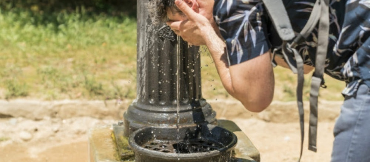 Imagen de archivo de un hombre refrescándose en una fuente