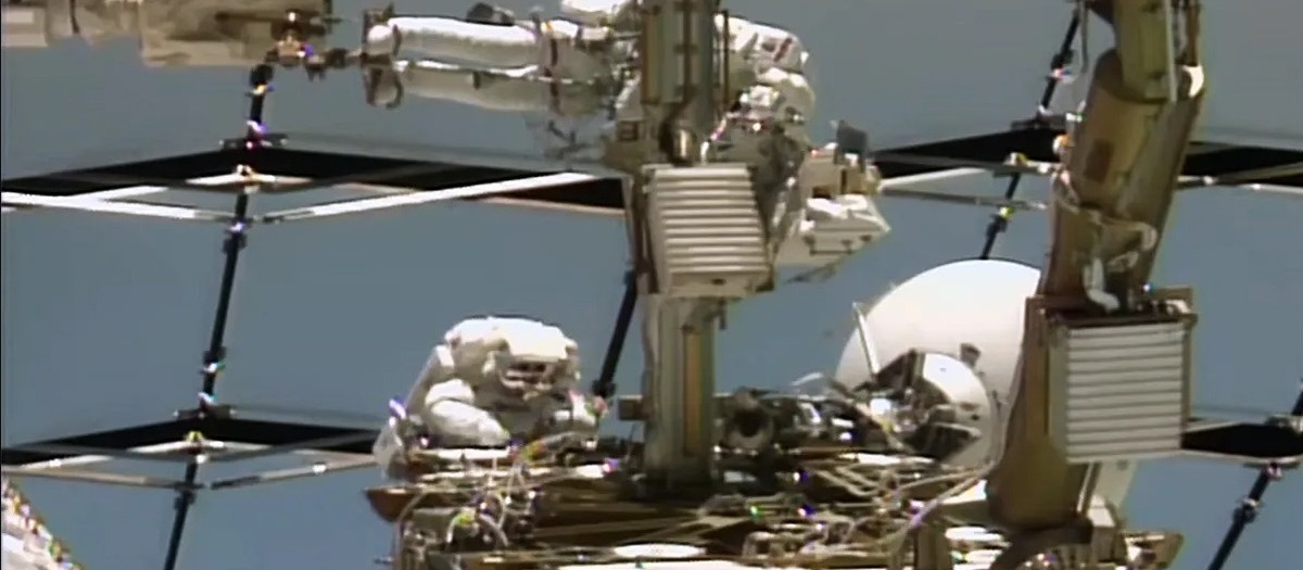 De arriba abajo, los astronautas Anil Menon de la NASA y Sophie Adenot de la ESA (Agencia Espacial Europea) trabajan en una antena de comunicación espacio-tierra en el exterior de la Estación Espacial Internacional