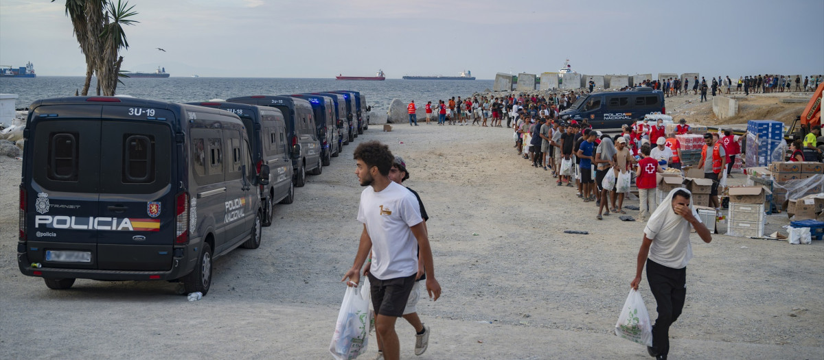 Varios inmigrantes hacen cola para que les den comida en una playa, a 19 de agosto de 2026, en Ceuta (España)