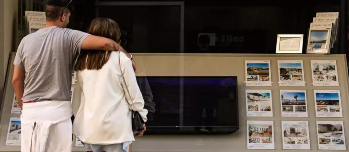 Imagen de archivo de dos jóvenes mirando pisos en una inmobiliaria