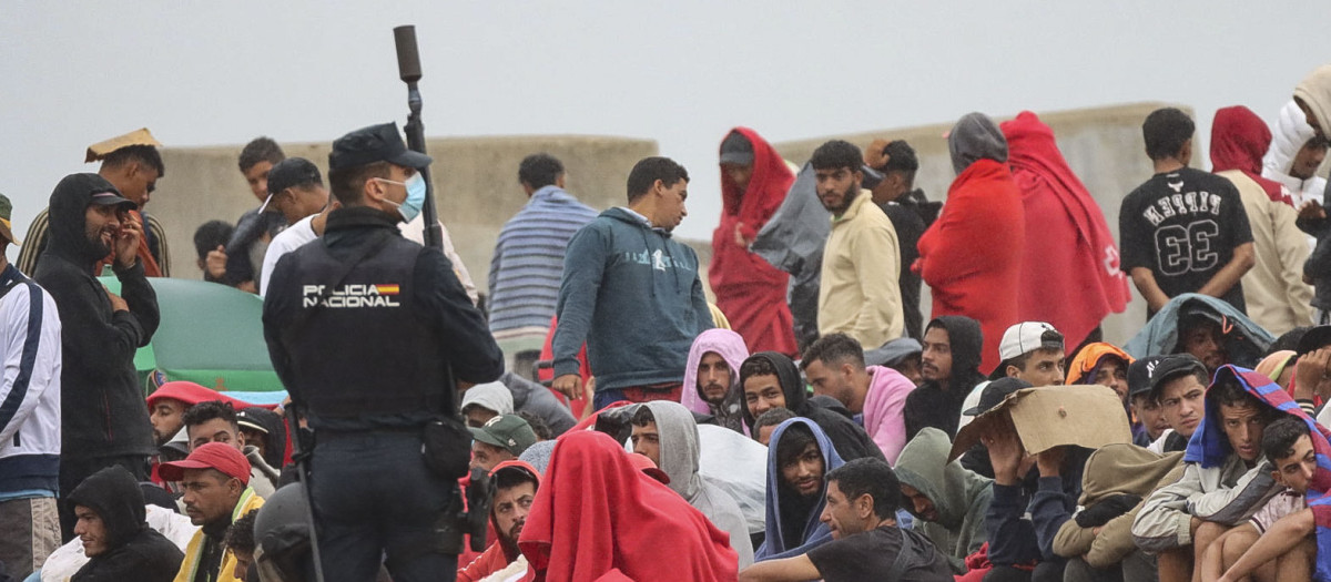 CEUTA, 21/08/2026.- La policía vigila a inmigrantes que continúan viviendo en las inmediaciones de la playa del Trampolín en Ceuta, este viernes. El secretario de Estado Juventud e Infancia, Rubén Pérez Correa, ha considerado "factible" llevar a cabo "en un plazo de pocas semanas" el traslado de 500 niñas migrantes no acompañadas desde Ceuta a la Península y, para ello, confía en la "voluntad" del Gobierno de la ciudad autónoma. EFE/Reduan