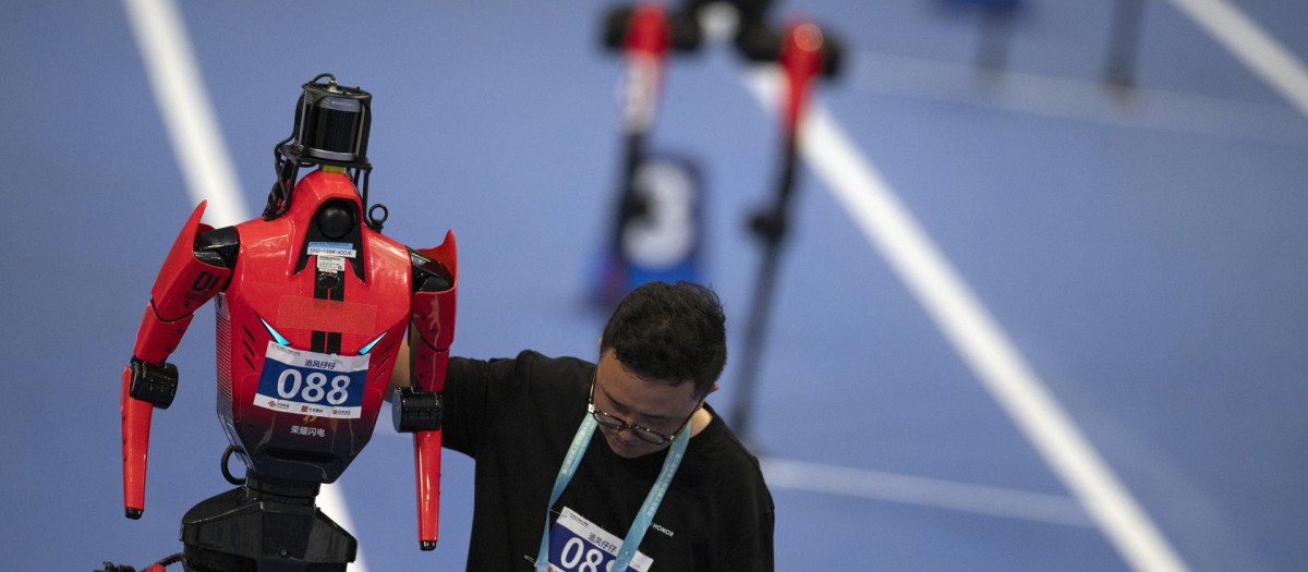 BEIJING (China), 23/08/2026.-Un miembro del equipo prepara un robot humanoide para la prueba de 400 metros