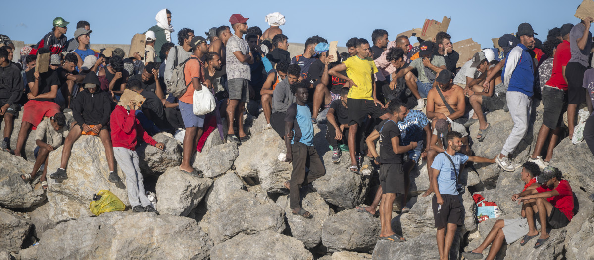 Miembros de la Cruz Roja reparten comida a los inmigrantes en una playa, a 21 de agosto de 2026