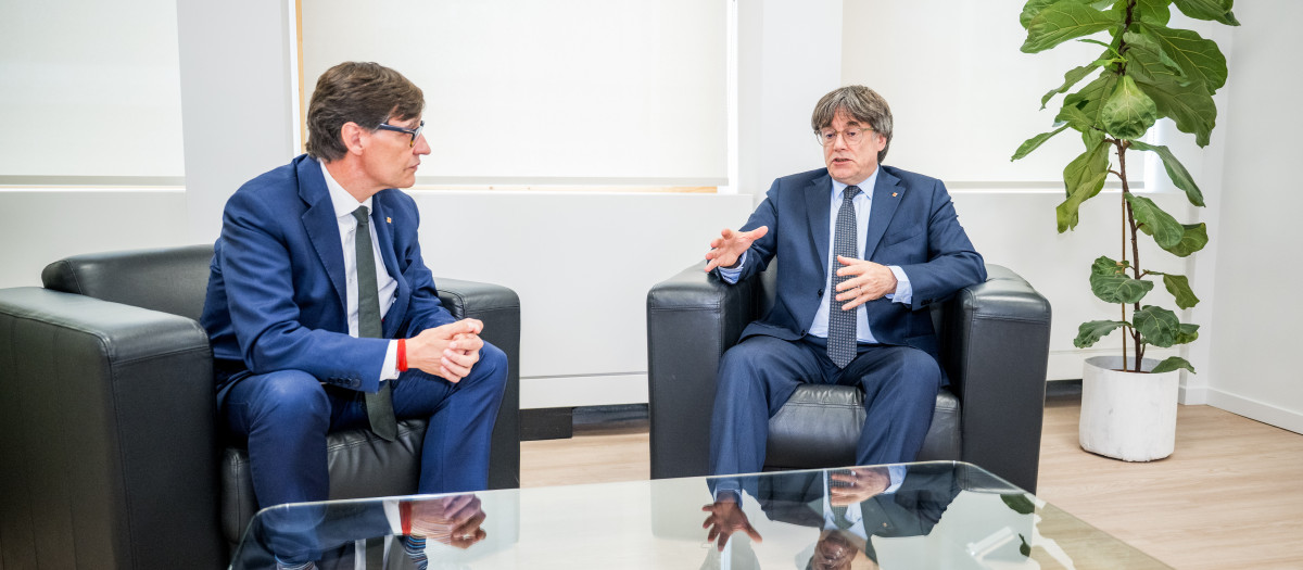 El presidente de la Generalitat, Salvador Illa (i), saluda al presidente de Junts per Catalunya, Carles Puigdemont (d), durante una reunión, a 2 de agosto de 2025, en Bruselas (Bélgica).