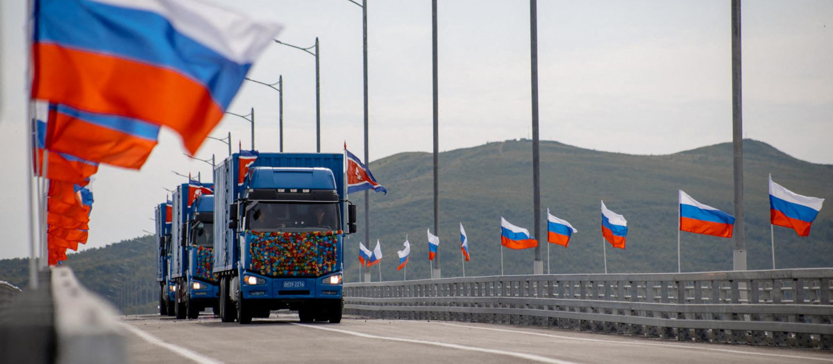 s banderas nacionales de Rusia ondean al viento y camiones norcoreanos cruzan el nuevo puente de carretera Rusia-Corea del Norte sobre el río Tumen, durante la ceremonia de inauguración.